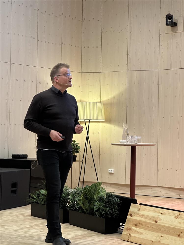 Lage Lyche snakker og viser med peker mens han går på gulvet - Klikk for stort bilde